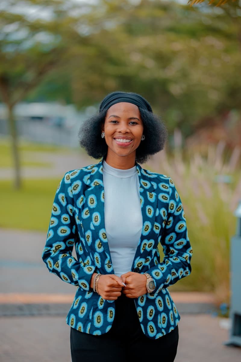 A woman wearing a tailored blazer in bold blue, gold, and black eye-motif ankara print