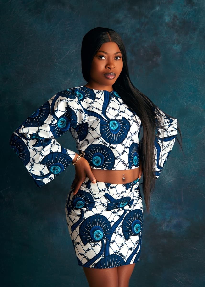 A woman wearing a matching navy and white eye-motif ankara crop top and mini skirt set