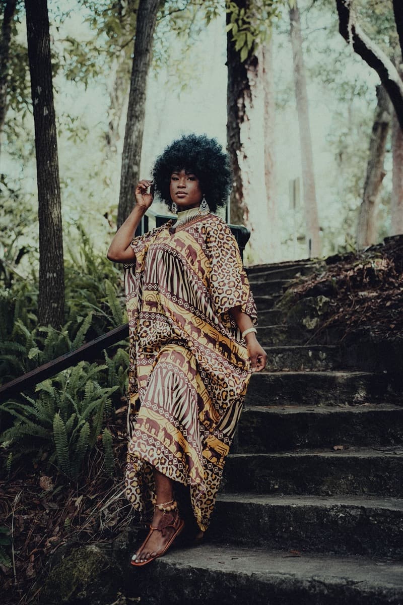 A woman with a natural afro descending stone steps in a flowing leopard and zebra-print bubu gown with dramatic wide sleeves
